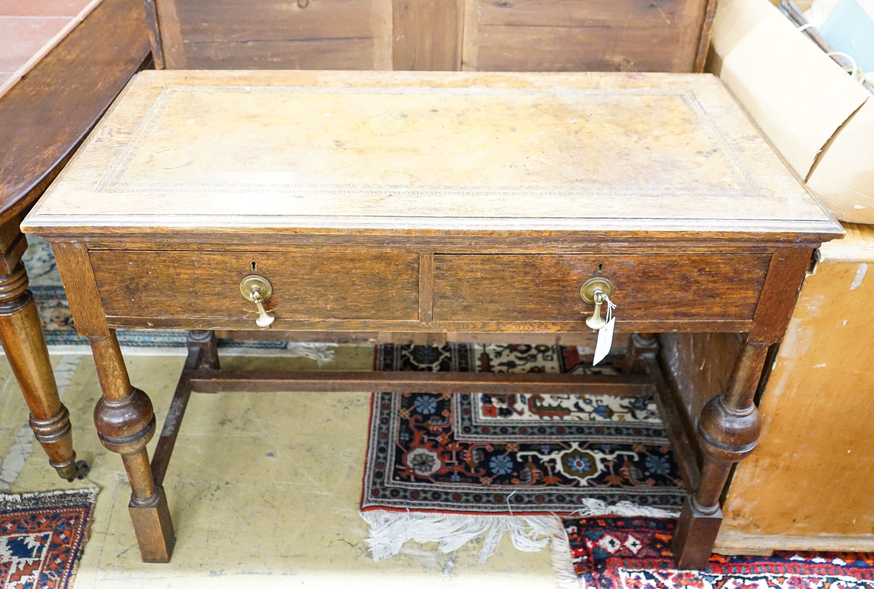 A 1920's oak two drawer writing table, with a leather inset top, length 106cm, depth 52cm, height 75cm